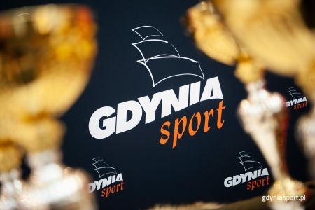 logo Gdynia Sport na granatowym tle wokół złotych pucharów