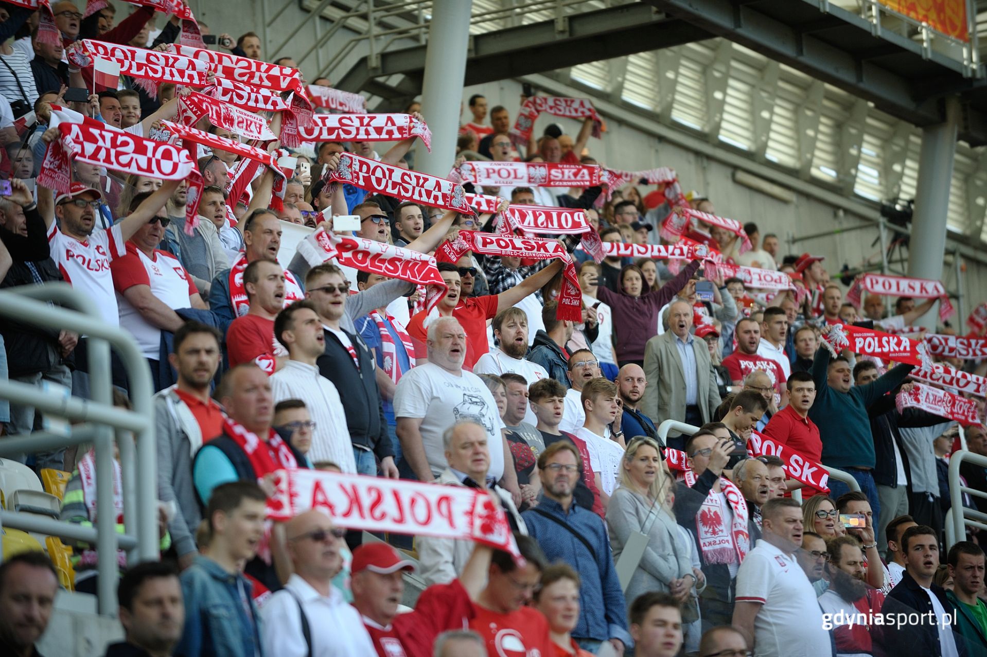 Kibice reprezentacji z podniesionymi szalikami na Stadionem Miejskim w Gdyni 