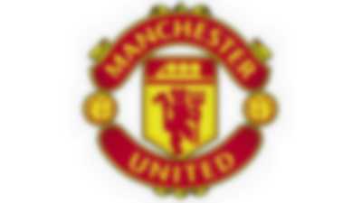 Herb zespołu Machester United - czerwony diabeł na żółty tle z napisem Manchester i United oraz dwiema piłkami po bokach